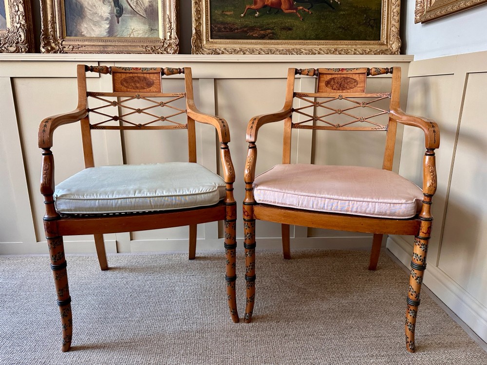 A pair of Edwardian Sheraton Revival painted wooden elbow chairs featuring woven cane seats, lattice backrests, and floral painted decoration. View VIII