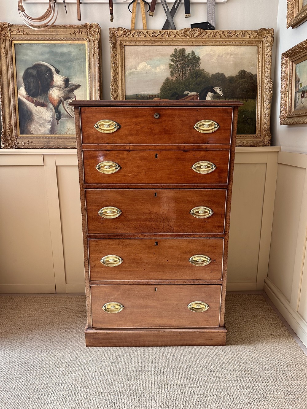 An antique nineteenth-century mahogany Wellington secretaire chest with an open drop-front writing desk section revealing internal pigeonholes above three lower drawers. View II