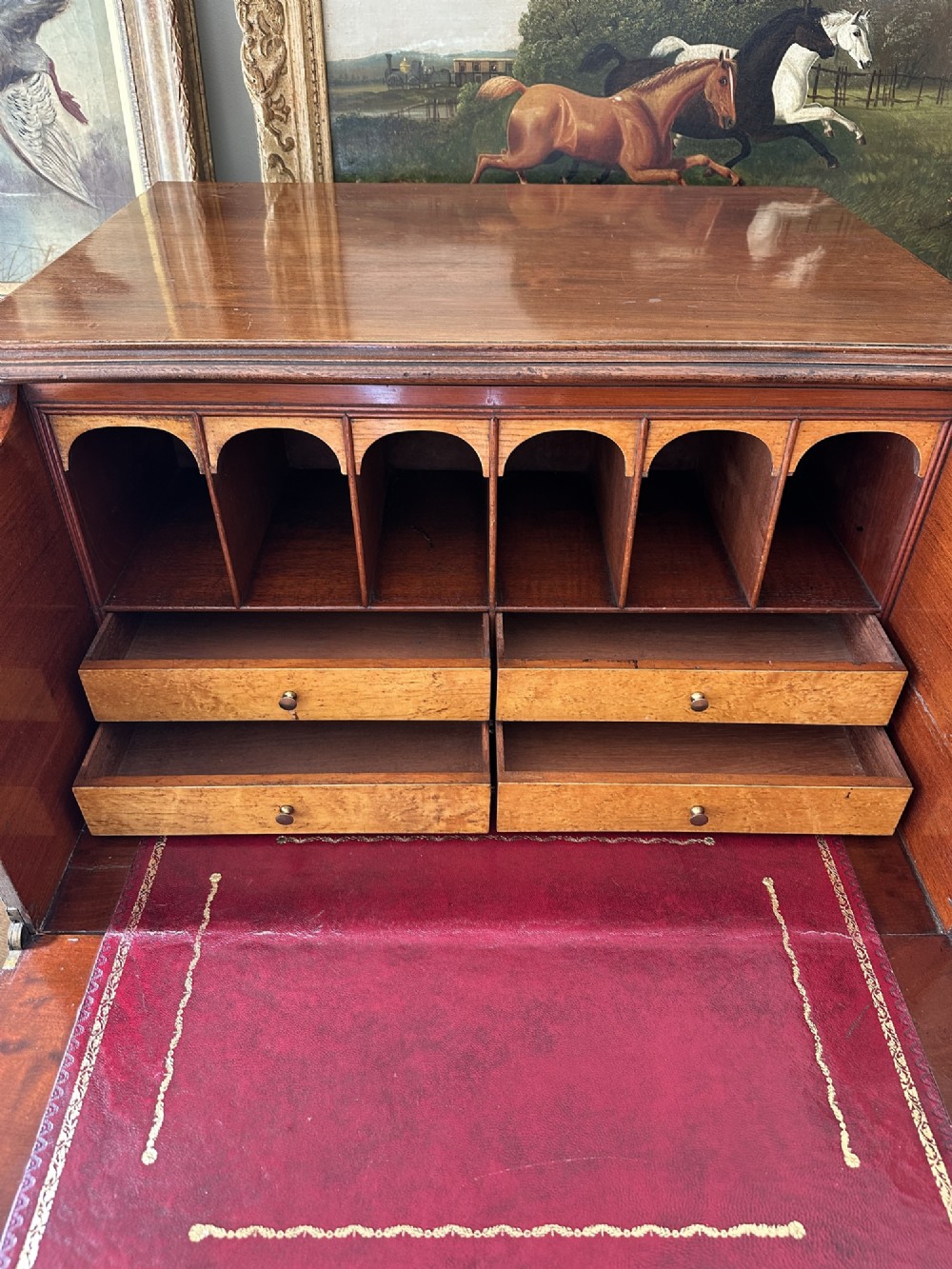 An antique nineteenth-century mahogany Wellington secretaire chest with an open drop-front writing desk section revealing internal pigeonholes above three lower drawers. View III