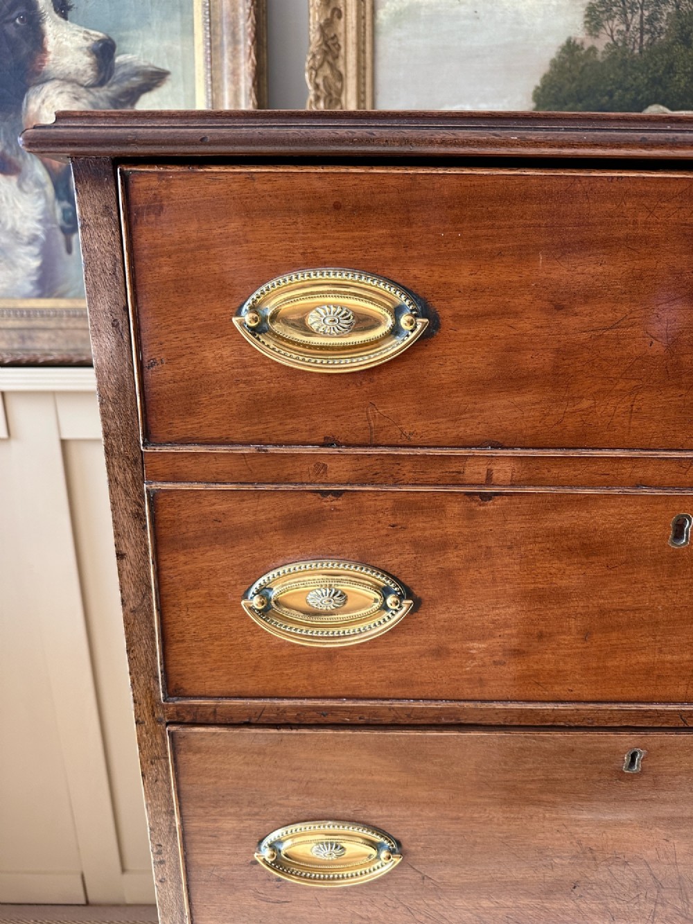 An antique nineteenth-century mahogany Wellington secretaire chest with an open drop-front writing desk section revealing internal pigeonholes above three lower drawers. View VII