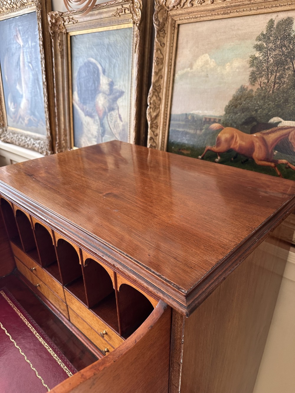 An antique nineteenth-century mahogany Wellington secretaire chest with an open drop-front writing desk section revealing internal pigeonholes above three lower drawers. View VIII