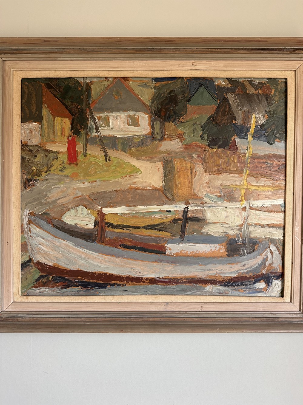 A framed mid-century oil painting depicting a harbour scene with grounded fishing boats and small coastal village houses rendered in textured impasto strokes and muted earth tones. View II