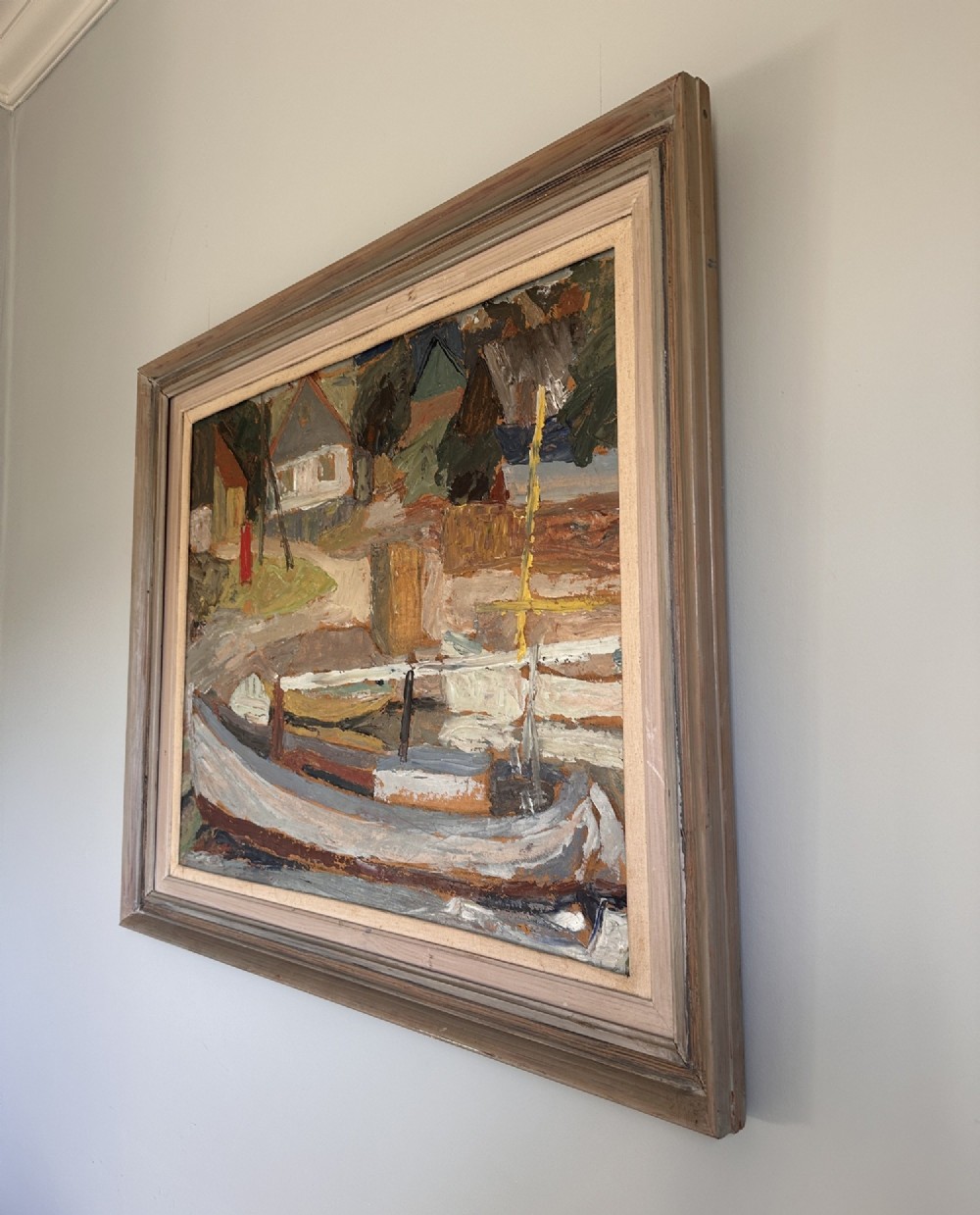 A framed mid-century oil painting depicting a harbour scene with grounded fishing boats and small coastal village houses rendered in textured impasto strokes and muted earth tones. View III