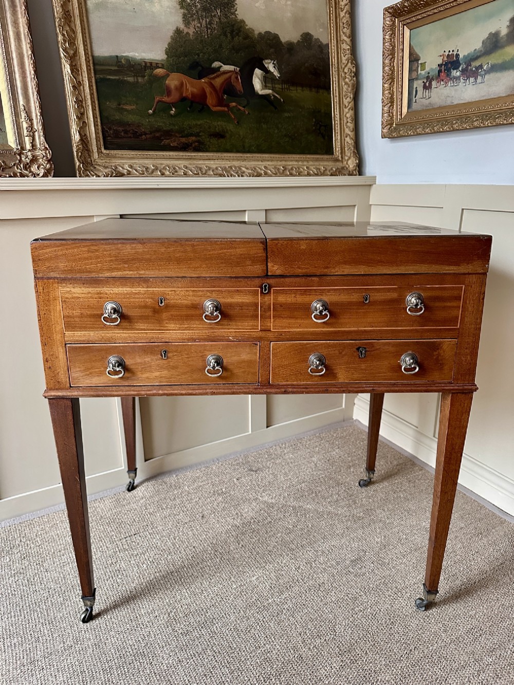 A late Georgian mahogany gentlemans dressing table featuring two hinged side leaves open to reveal internal compartments and a central adjustable mirror, raised on square tapered legs with brass castors. View VIII