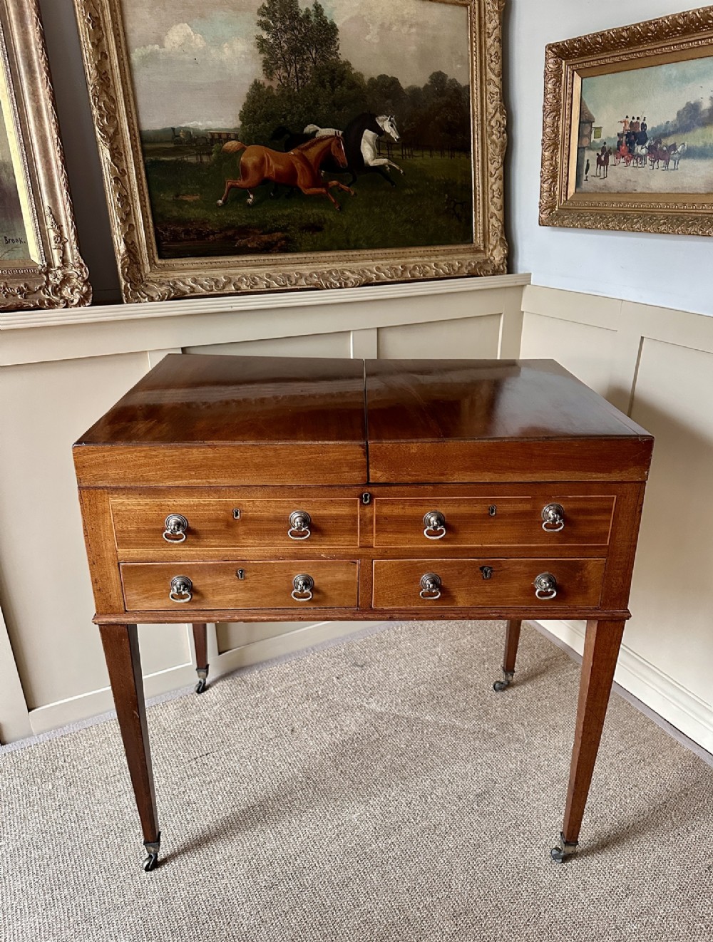 A late Georgian mahogany gentlemans dressing table featuring two hinged side leaves open to reveal internal compartments and a central adjustable mirror, raised on square tapered legs with brass castors. View IX