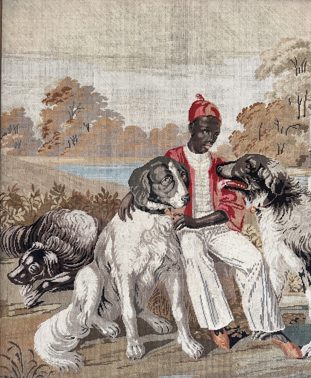 A framed Victorian Berlin woolwork tapestry depicting a seated figure with two dogs in a parkland setting within a moulded gilt frame. View II