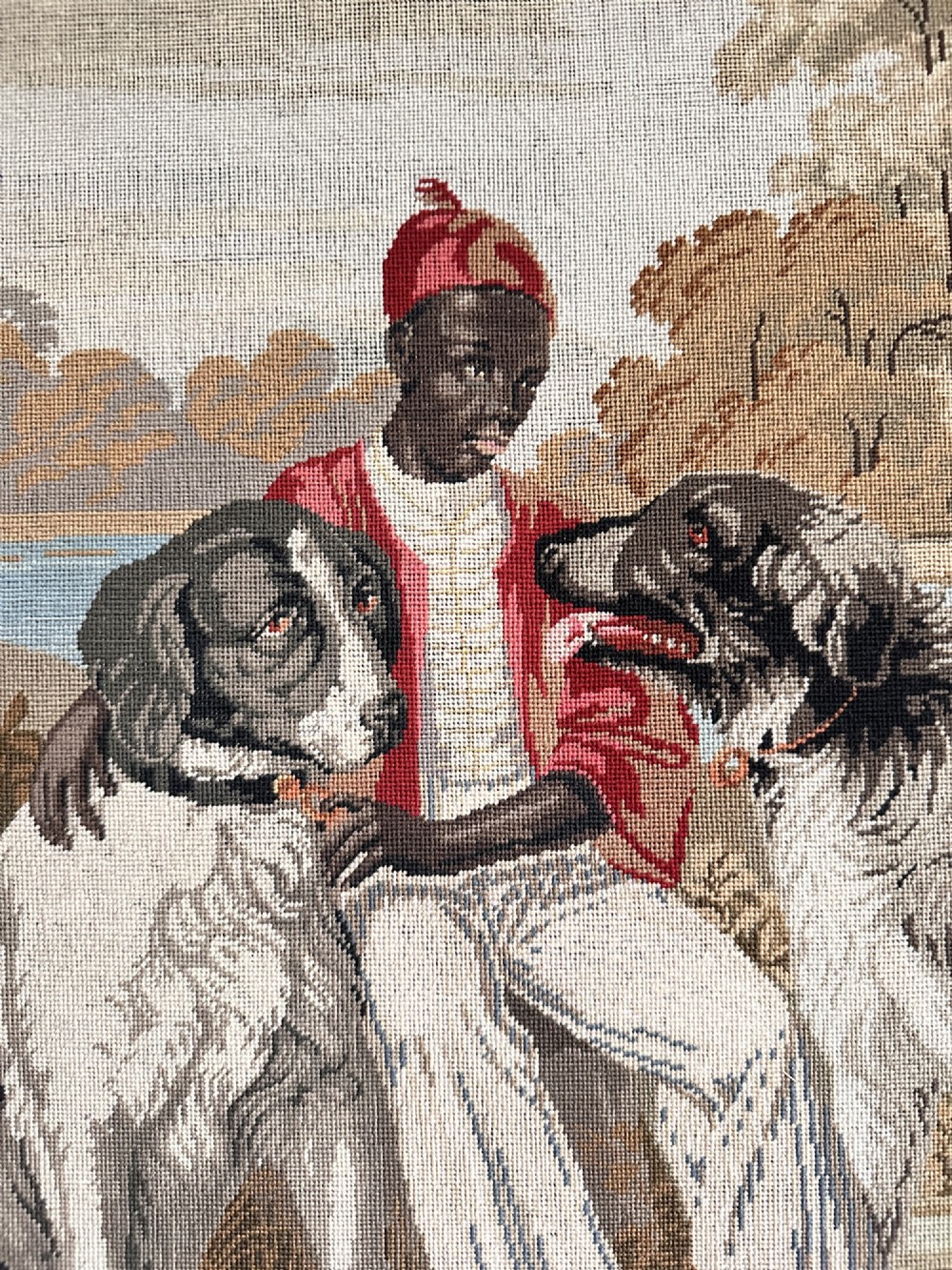A framed Victorian Berlin woolwork tapestry depicting a seated figure with two dogs in a parkland setting within a moulded gilt frame. View IV