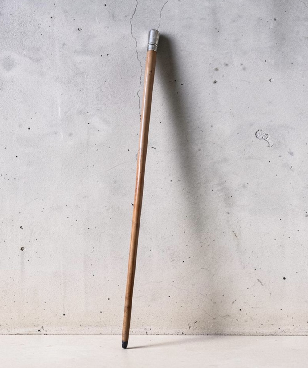 An antique malacca wood walking cane featuring a polished silver collar and cap.