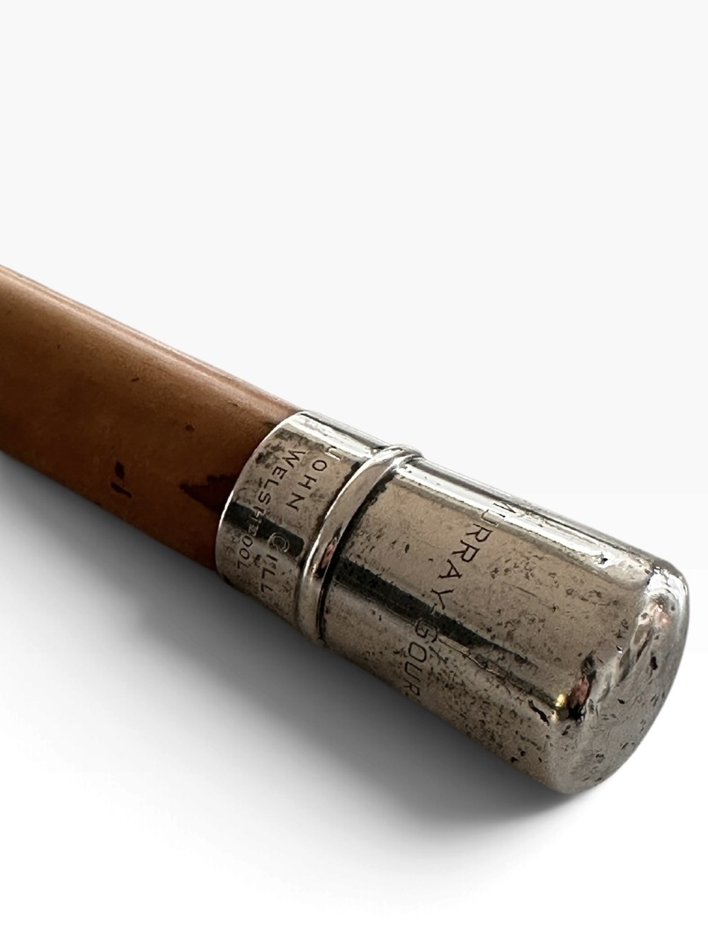 An antique malacca wood walking cane featuring a polished silver collar and cap. View IV