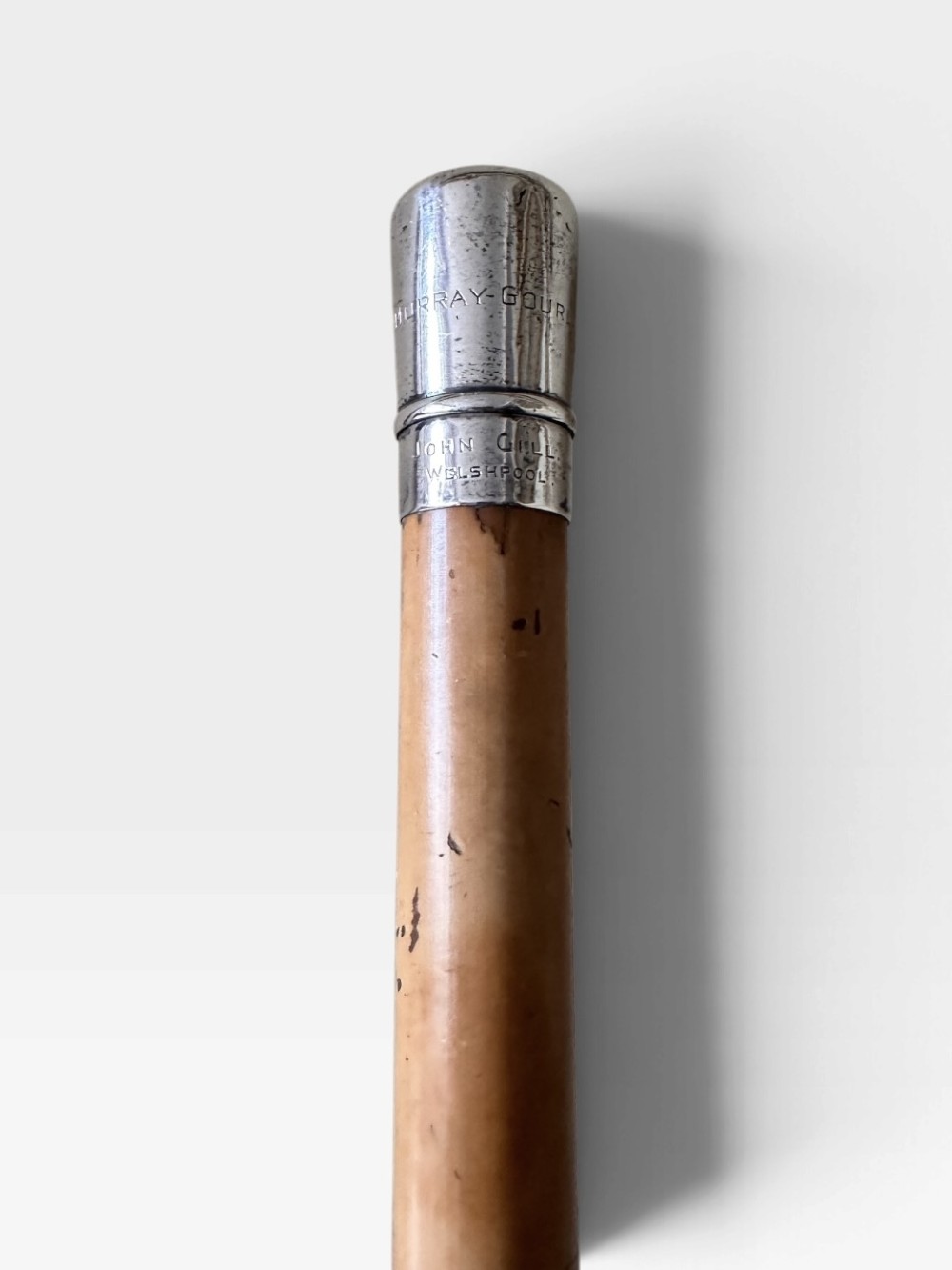 An antique malacca wood walking cane featuring a polished silver collar and cap. View VI