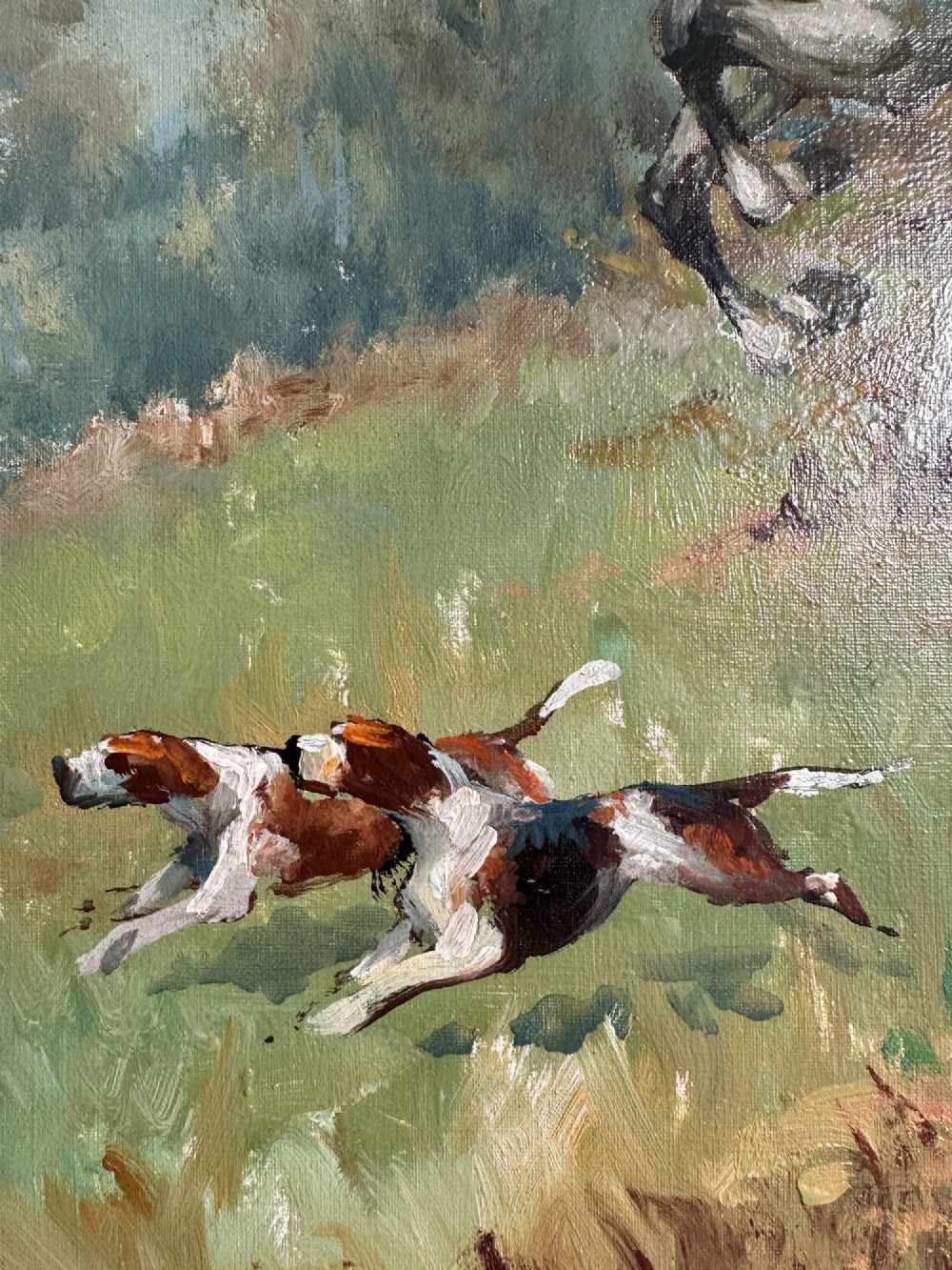 An oil painting depicting a fox hunting scene with horse riders and foxhounds across a green countryside landscape, presented in a gold gilded wooden frame. View IV