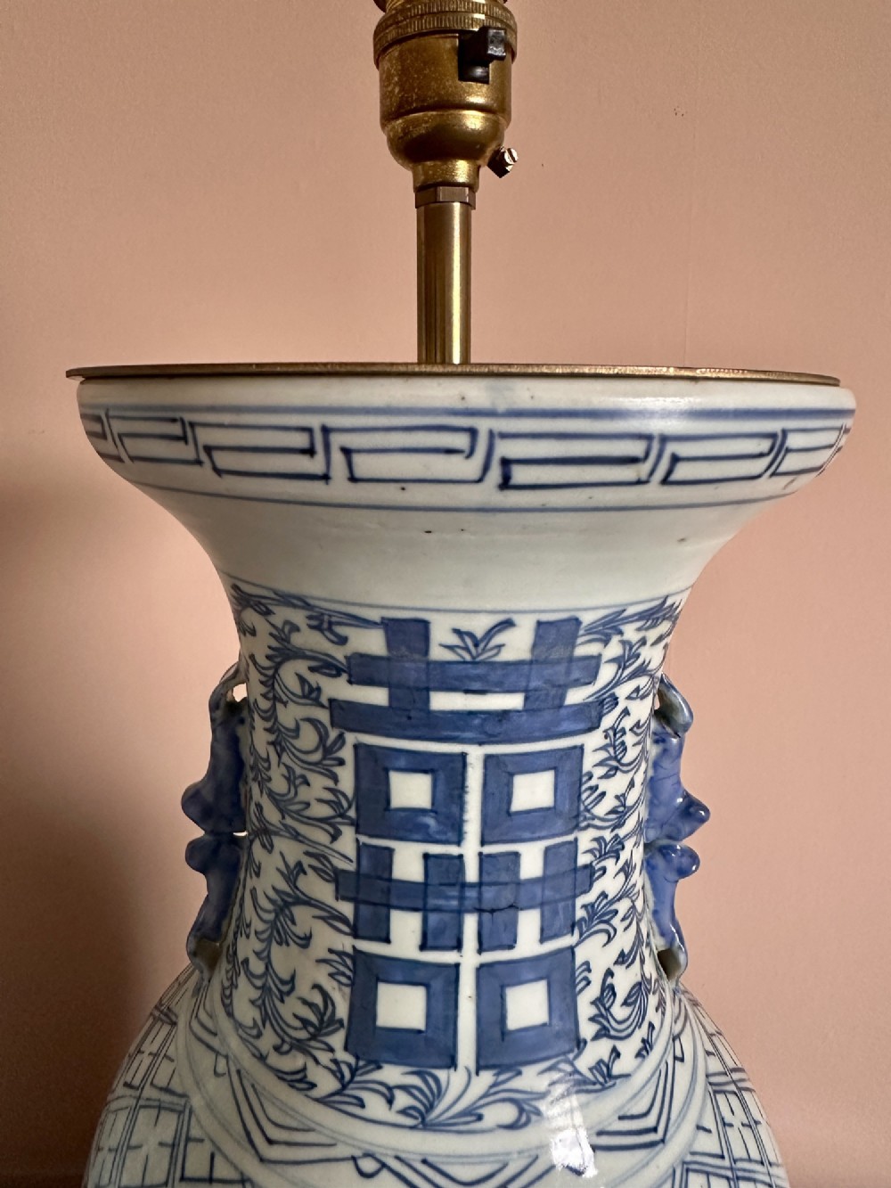 A pair of baluster-shaped blue and white Chinese porcelain table lamps featuring hand-painted Double Happiness symbols and floral scrolls set on dark carved wooden bases. View VI