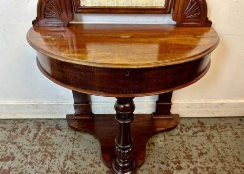 fig 1. A late 19th-century Victorian mahogany Duchess dressing table with an arched mirror frame, carved cresting, turned central leg, and shaped plinth base.