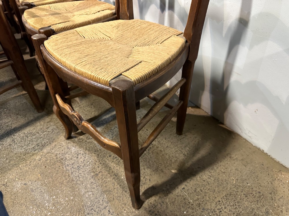 A set of twelve French provincial ladder back dining chairs featuring woven rush seats and carved timber frames. View III