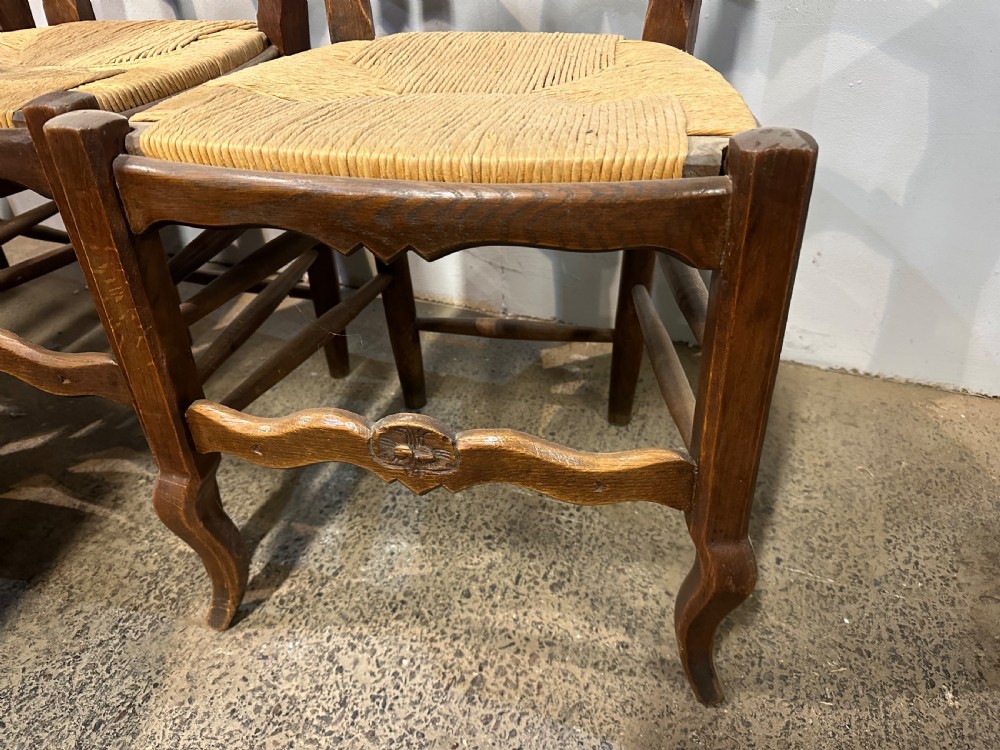 A set of twelve French provincial ladder back dining chairs featuring woven rush seats and carved timber frames. View IV