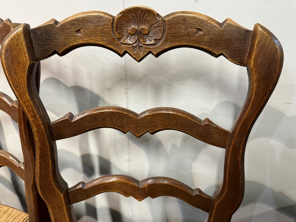 A set of twelve French provincial ladder back dining chairs featuring woven rush seats and carved timber frames. View V