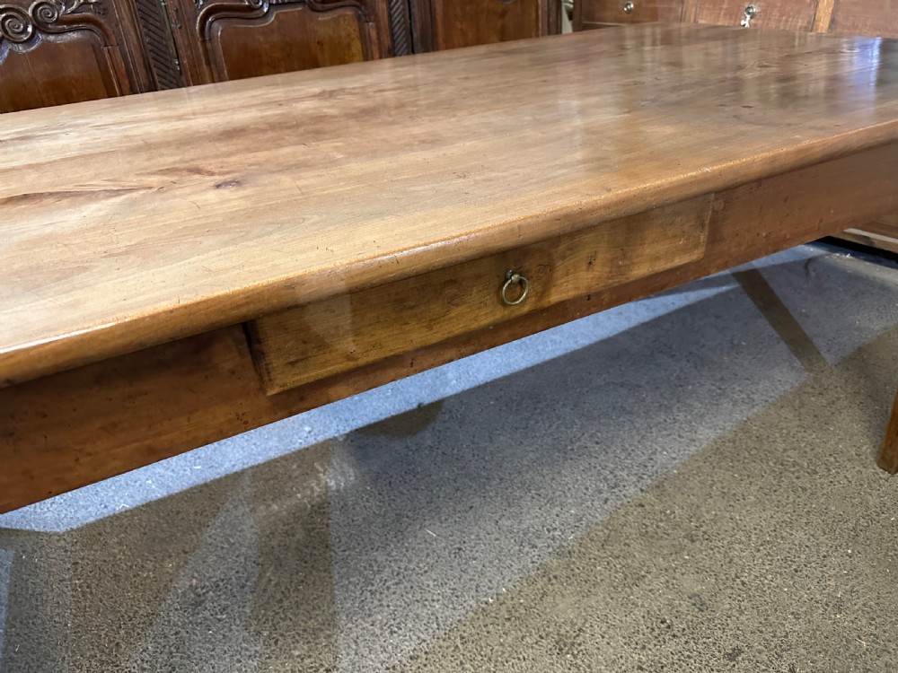 A 19th-century wide cherry wood dining table featuring a plank top, tapered square legs, and a single frieze drawer. View IV