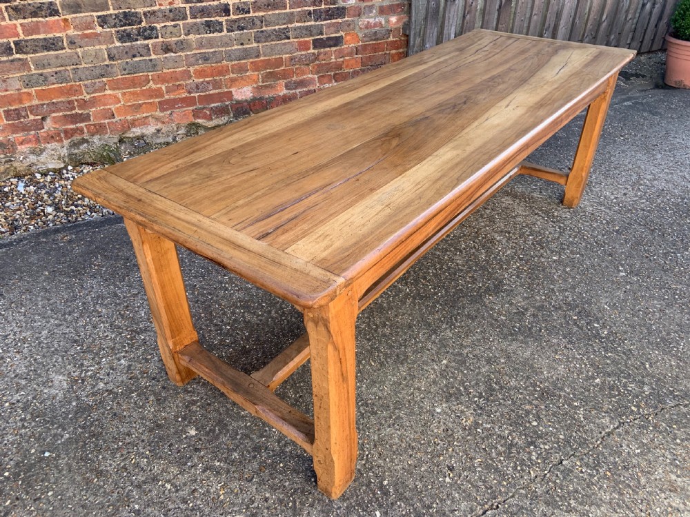 A late nineteenth-century pale walnut refectory dining table featuring a rectangular plank top with breadboard ends supported by legs joined by an H-stretcher.