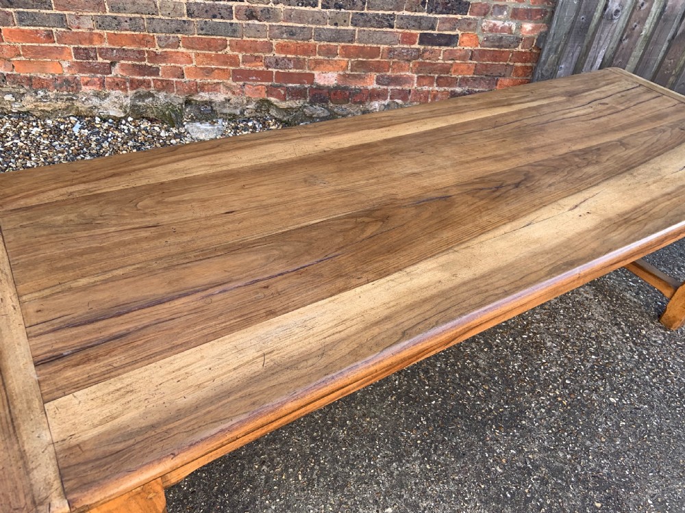 A late nineteenth-century pale walnut refectory dining table featuring a rectangular plank top with breadboard ends supported by legs joined by an H-stretcher. View II