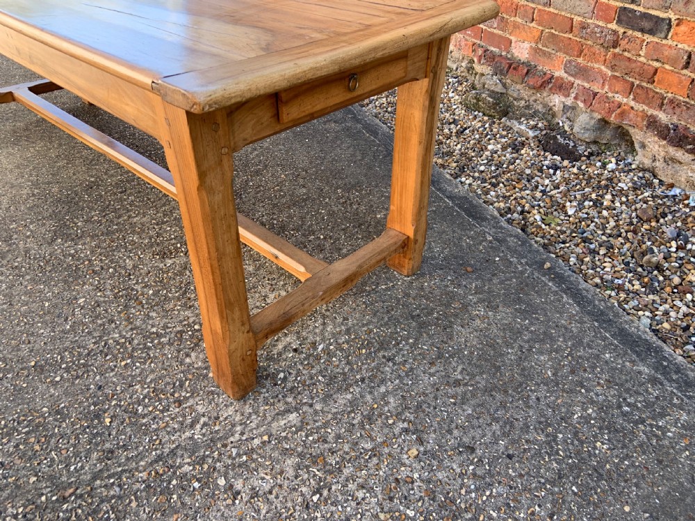 A late nineteenth-century pale walnut refectory dining table featuring a rectangular plank top with breadboard ends supported by legs joined by an H-stretcher. View III