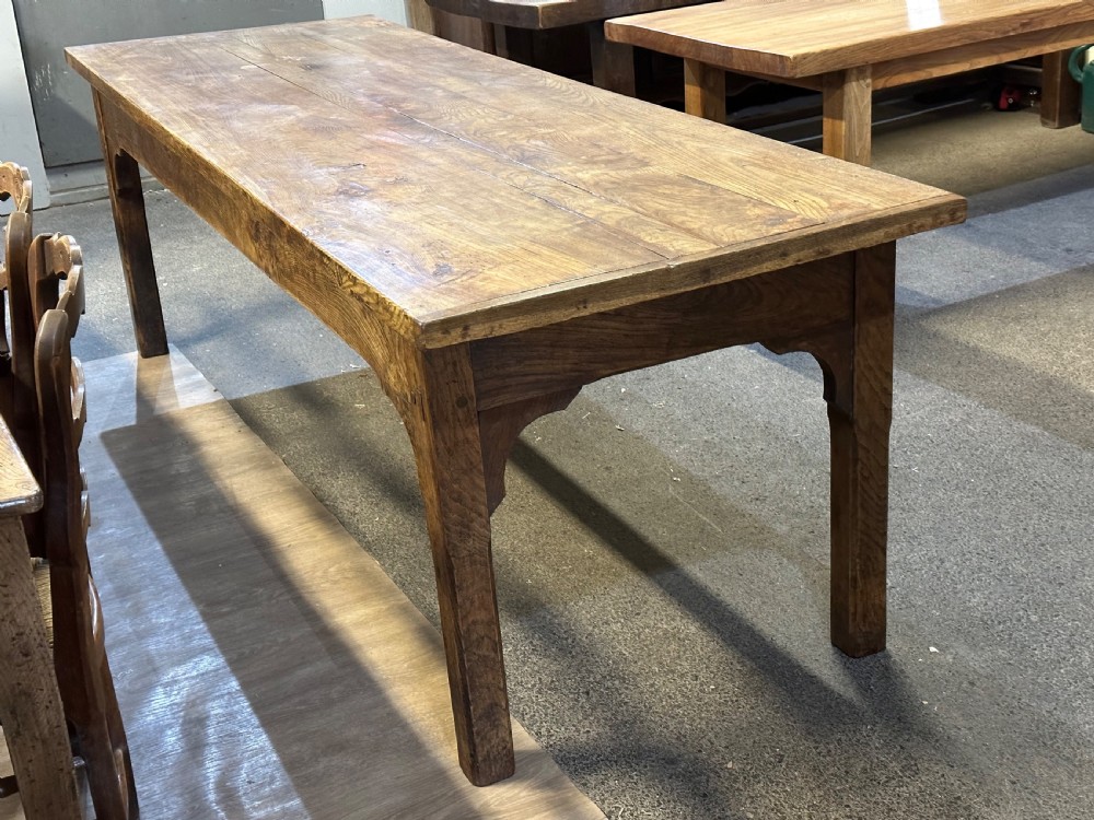 A nineteenth-century rectangular ash farmhouse dining table featuring a plank top, tapered square legs with corner brackets, and a natural aged wood grain finish.