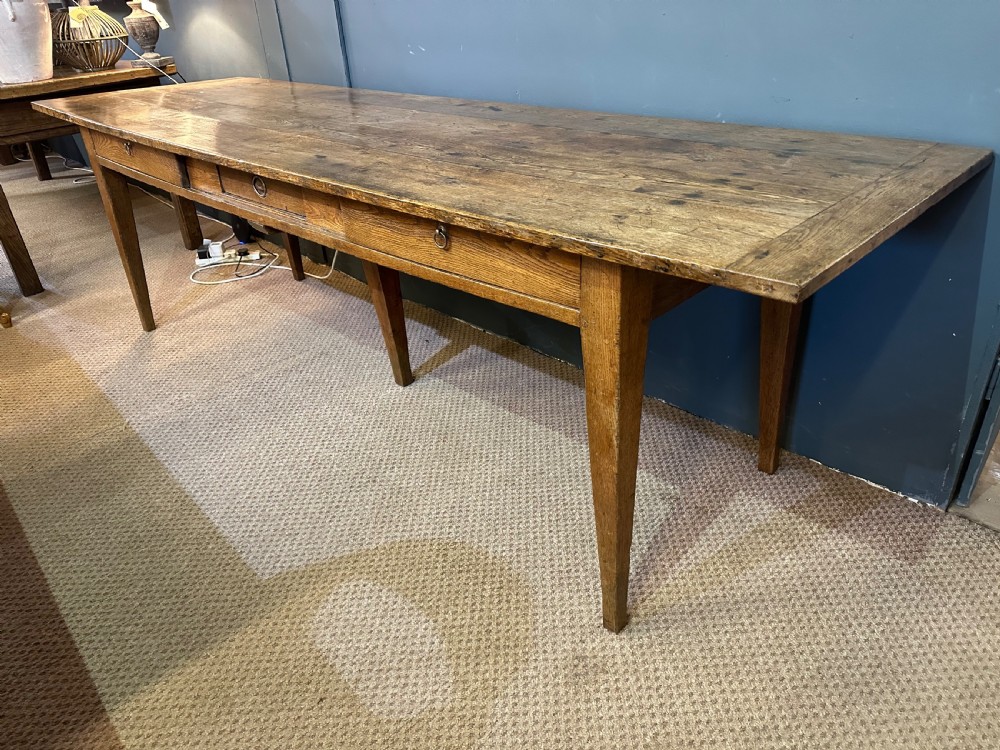 A long 19th-century oak table featuring a plank top, three front drawers with metal ring pulls, and four tapered square legs. View III