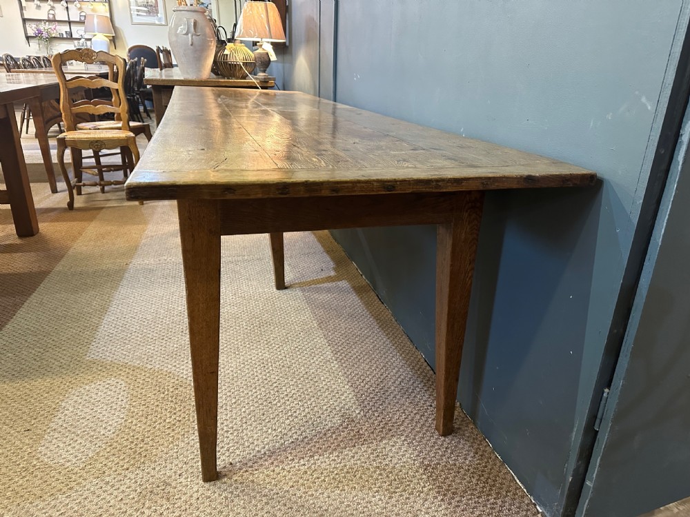 A long 19th-century oak table featuring a plank top, three front drawers with metal ring pulls, and four tapered square legs. View IV