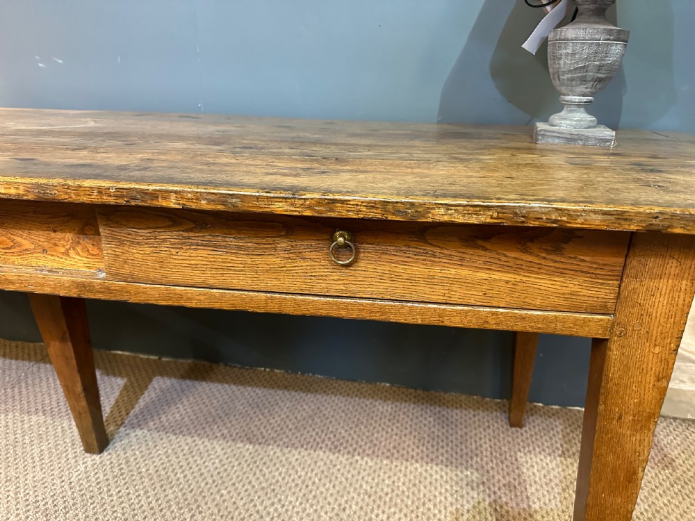 A long 19th-century oak table featuring a plank top, three front drawers with metal ring pulls, and four tapered square legs. View V