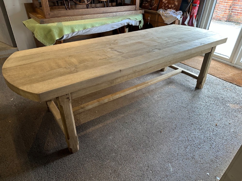 An overhead view of a long, bleached oak refectory table with rounded oval ends and sturdy stretcher-base legs. View II
