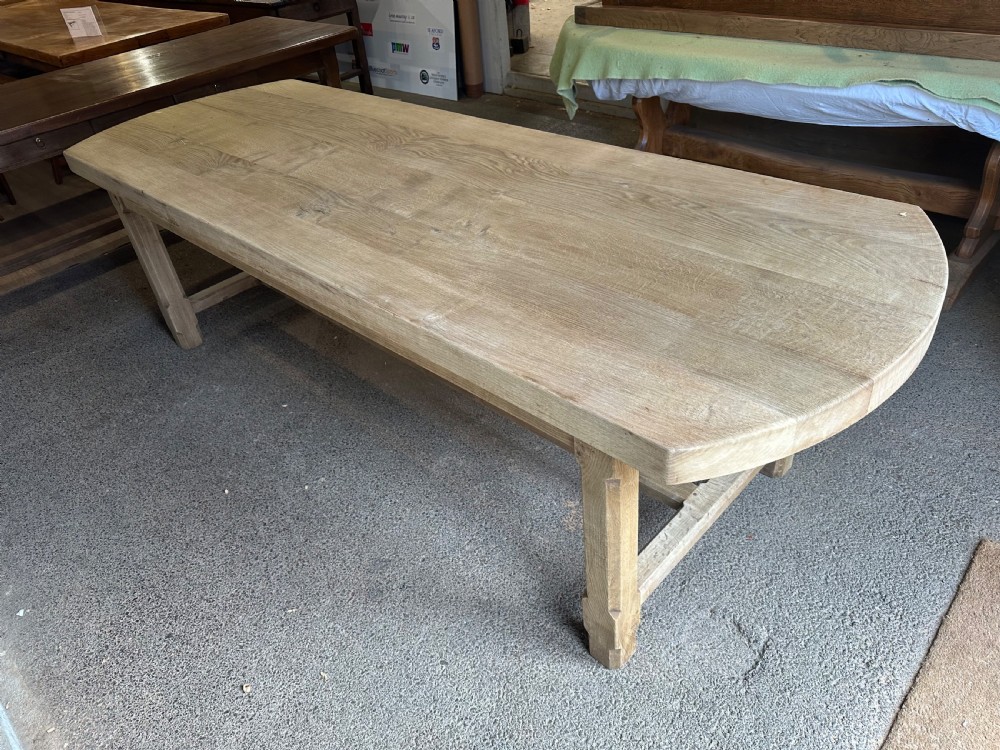 An overhead view of a long, bleached oak refectory table with rounded oval ends and sturdy stretcher-base legs. View III