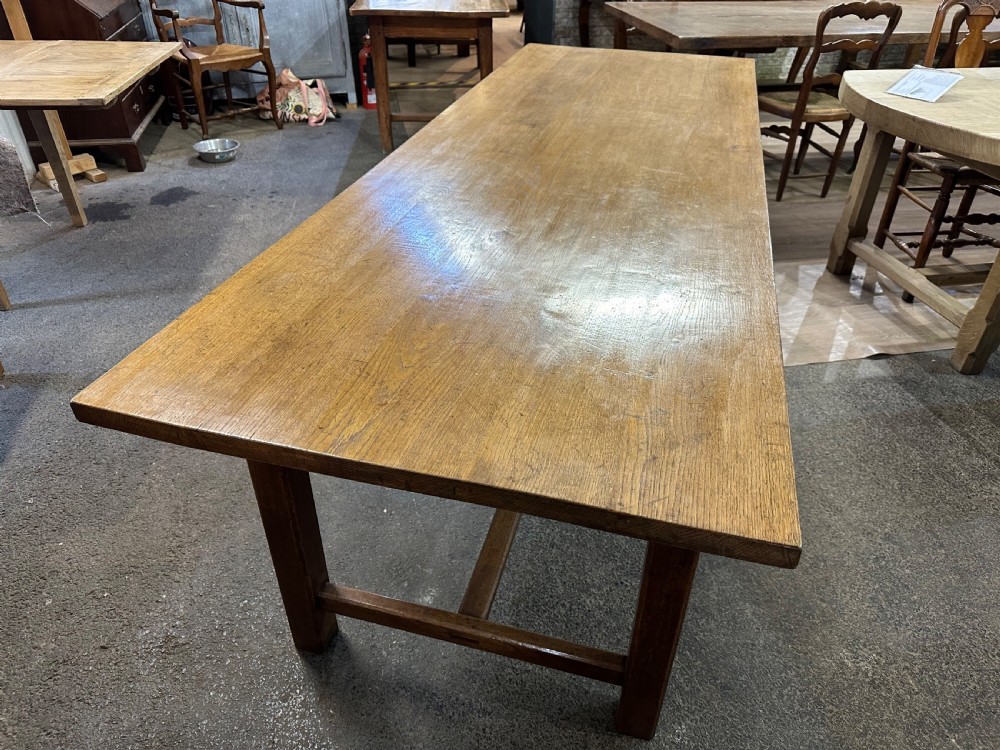 A long rectangular antique oak farmhouse dining table featuring a plank top and an H-stretcher base structure. View III