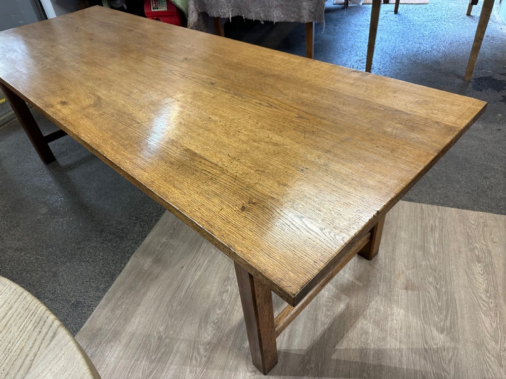A long rectangular antique oak farmhouse dining table featuring a plank top and an H-stretcher base structure. View V