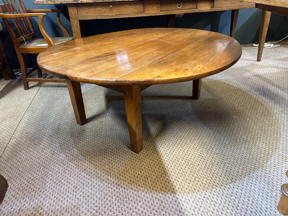 A nineteenth-century round cherrywood coffee table featuring two drop-leaf side flaps and straight wooden legs. View III