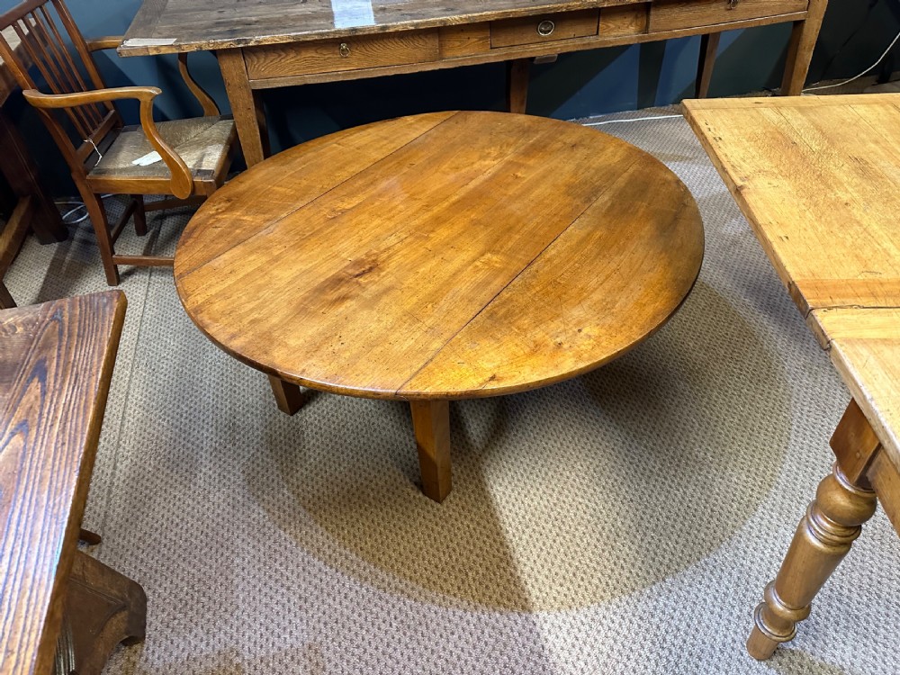 A nineteenth-century round cherrywood coffee table featuring two drop-leaf side flaps and straight wooden legs. View IV