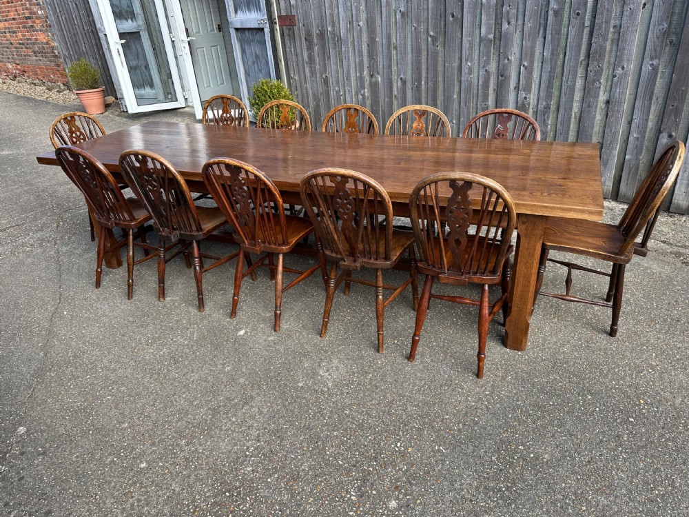 A set of twelve antique wooden Windsor dining chairs with hoop backs, pierced wheelback splats, contoured saddled seats, and turned legs with stretcher bases. View III