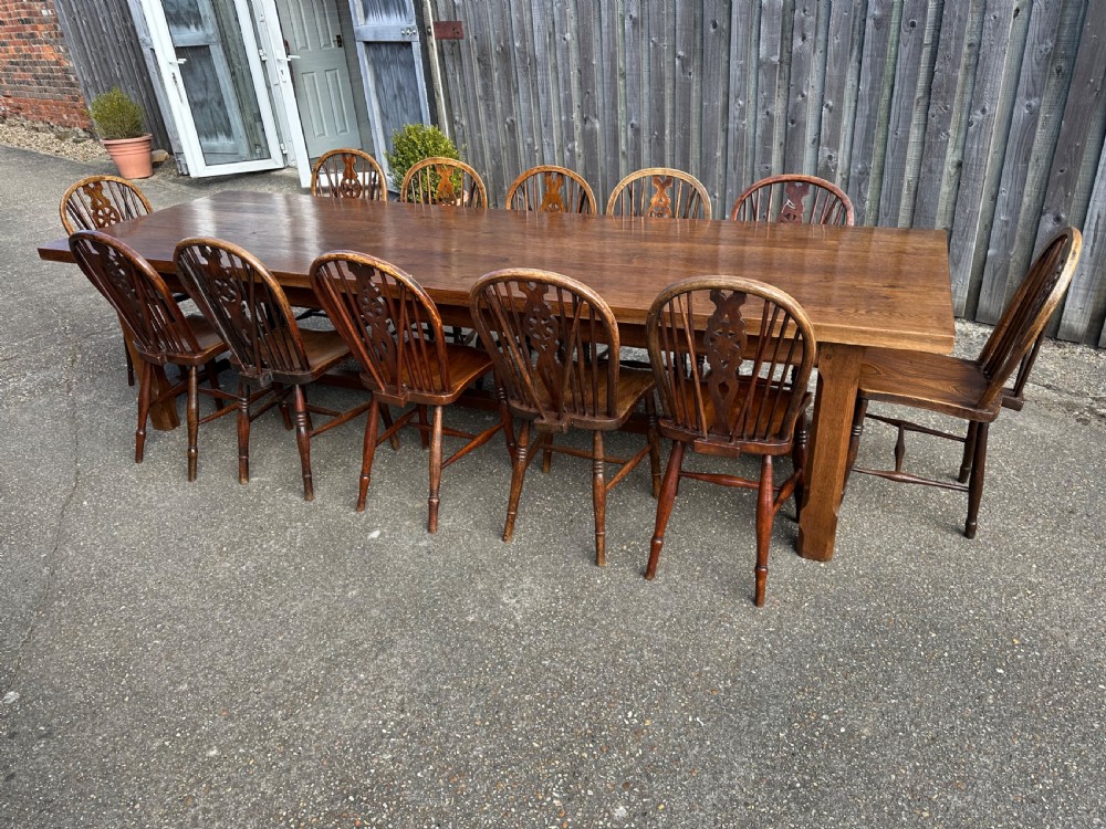 A set of twelve antique wooden Windsor dining chairs with hoop backs, pierced wheelback splats, contoured saddled seats, and turned legs with stretcher bases. View IV