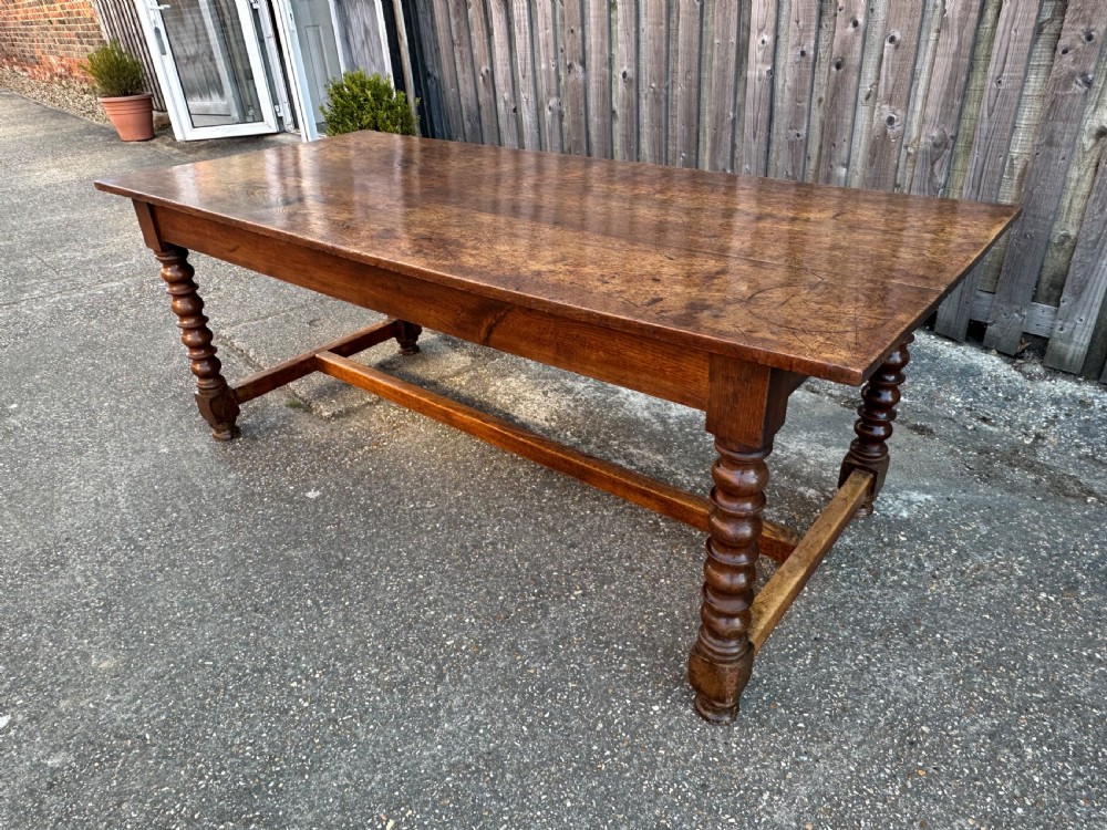 An 18th-century refectory dining table constructed with an elm plank top and an oak base featuring turned legs and lower stretchers. View II
