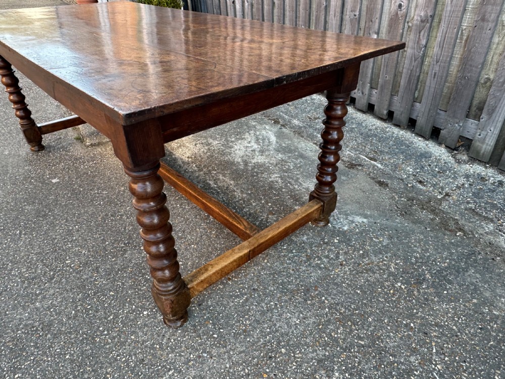 An 18th-century refectory dining table constructed with an elm plank top and an oak base featuring turned legs and lower stretchers. View III