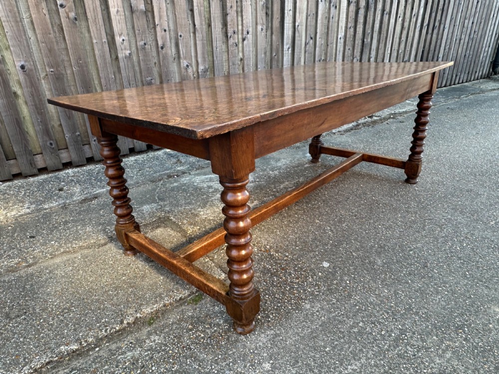 An 18th-century refectory dining table constructed with an elm plank top and an oak base featuring turned legs and lower stretchers. View IV