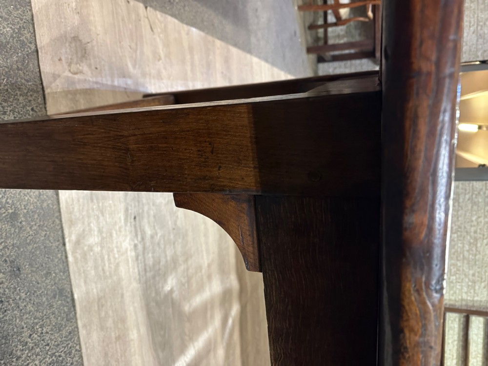 A long 18th-century dark wood farmhouse dining table featuring a plank top and square legs with end stretchers. View II