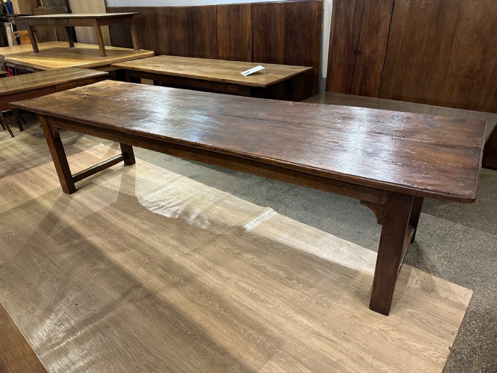 A long 18th-century dark wood farmhouse dining table featuring a plank top and square legs with end stretchers. View III