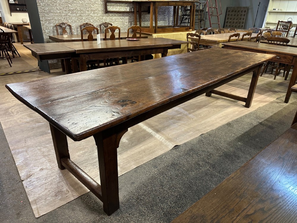 A long 18th-century dark wood farmhouse dining table featuring a plank top and square legs with end stretchers. View V