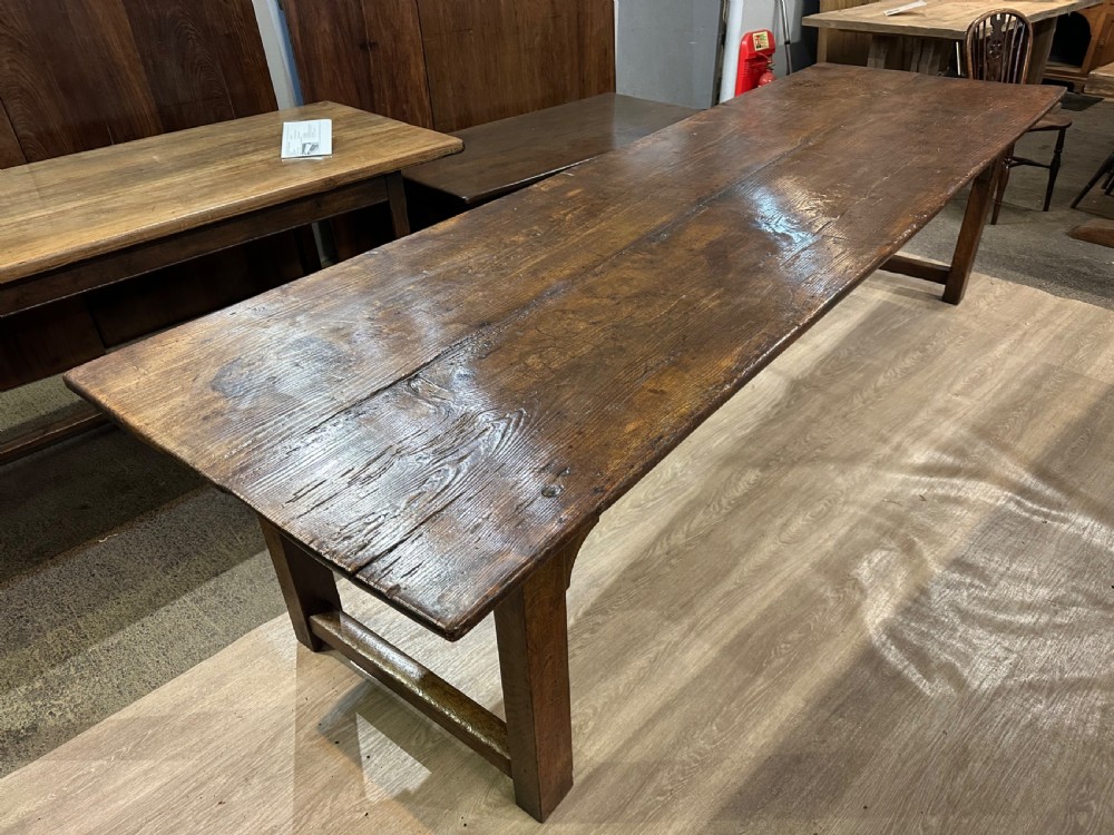 A long 18th-century dark wood farmhouse dining table featuring a plank top and square legs with end stretchers. View VI
