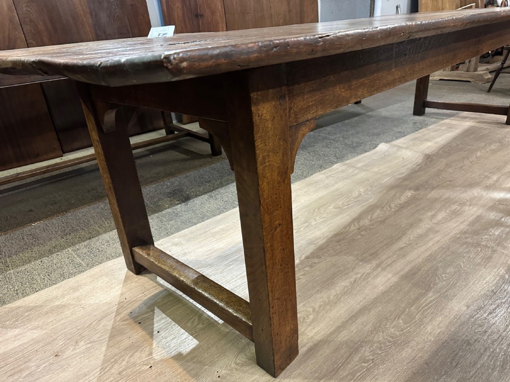 A long 18th-century dark wood farmhouse dining table featuring a plank top and square legs with end stretchers. View VII