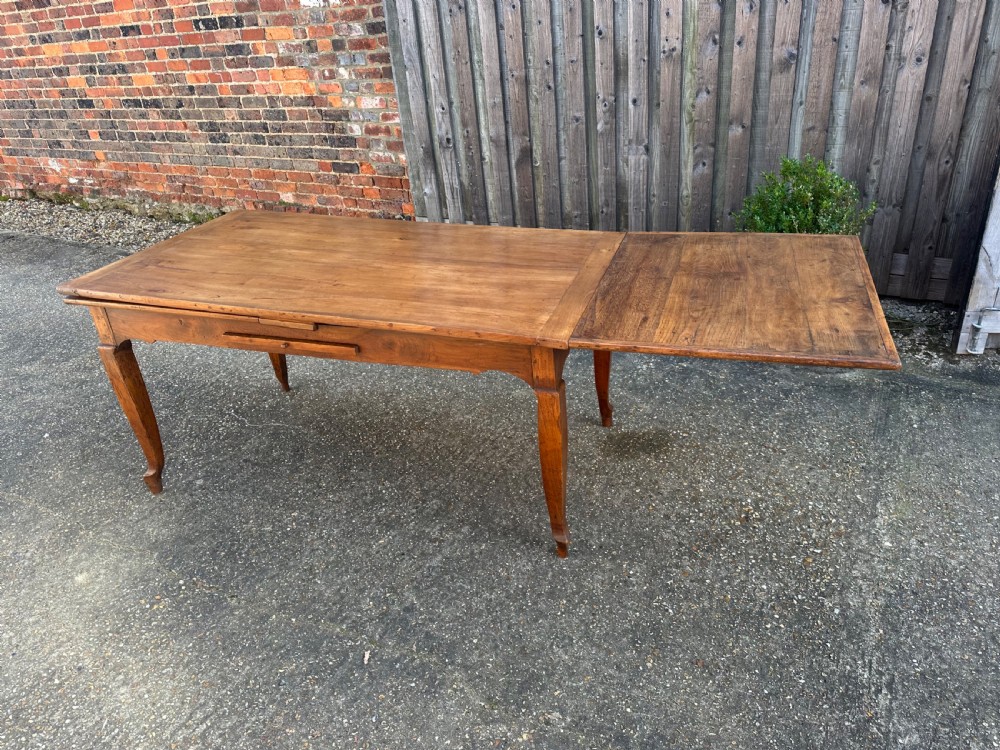 An antique cherry wood extending dining table with double draw-leaves, an integrated pull-out bread slide, and slender cabriole legs. View II
