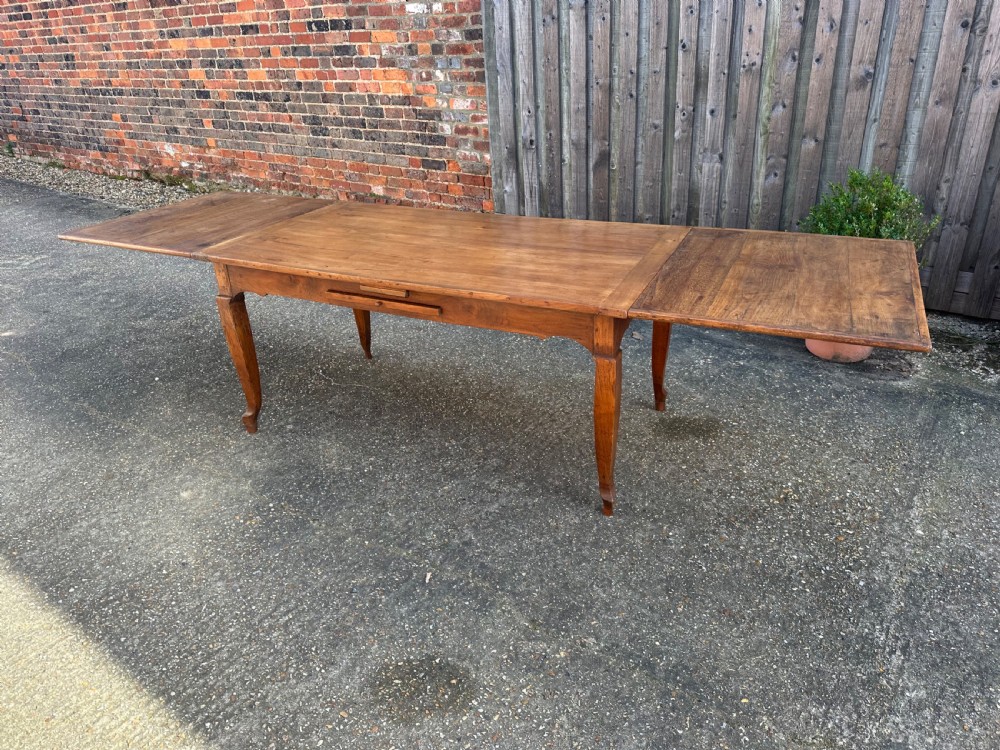 An antique cherry wood extending dining table with double draw-leaves, an integrated pull-out bread slide, and slender cabriole legs. View III