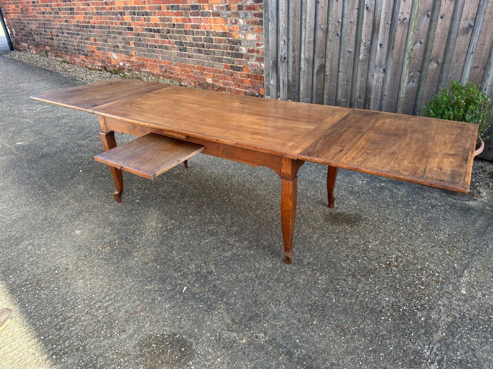 An antique cherry wood extending dining table with double draw-leaves, an integrated pull-out bread slide, and slender cabriole legs. View IV