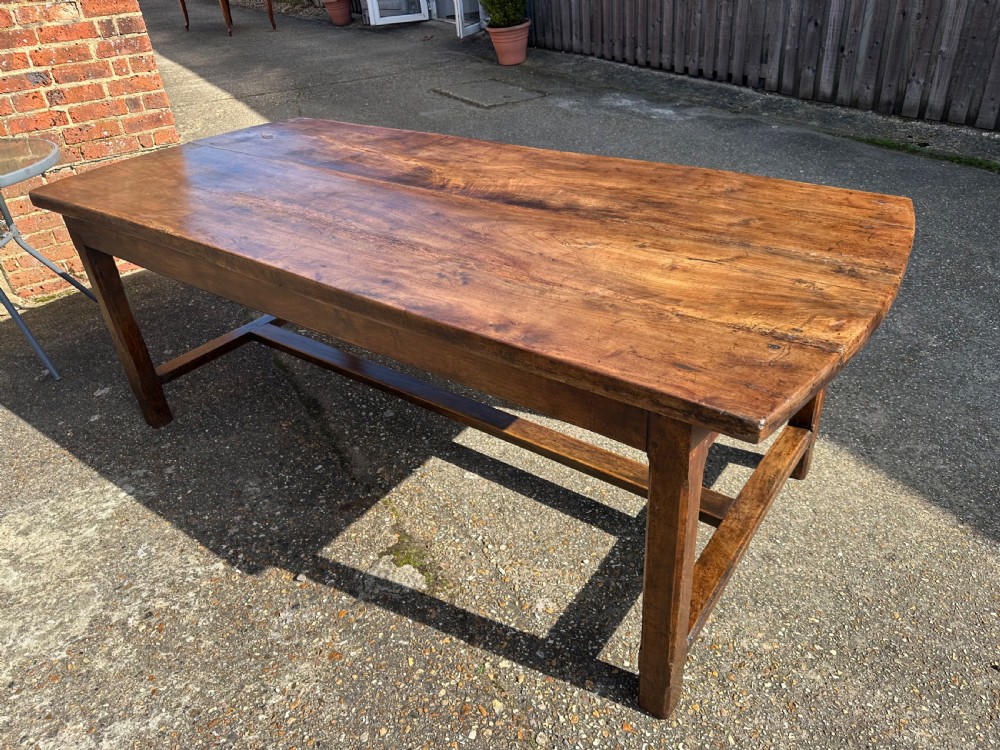 An early nineteenth-century solid walnut dining table featuring a wide plank top with natural patina and square legs linked by low stretchers. View II