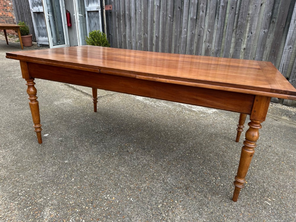 A 19th-century cherry wood extending dining table featuring turned legs and side extension leaves on a plain background. View III