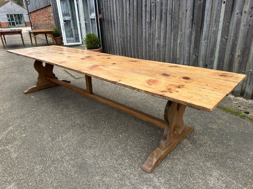 A long rectangular pine trestle dining table with a multi-plank top and a central timber stretcher base. View II